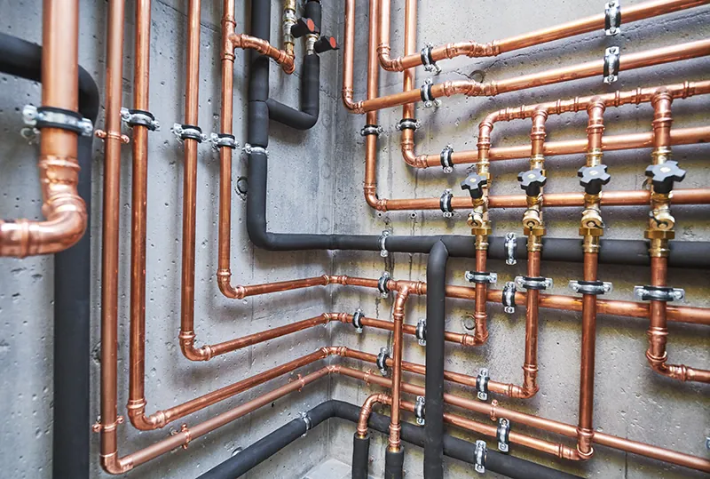 Copper supply lines and shutoff valves roughed in on a concrete wall