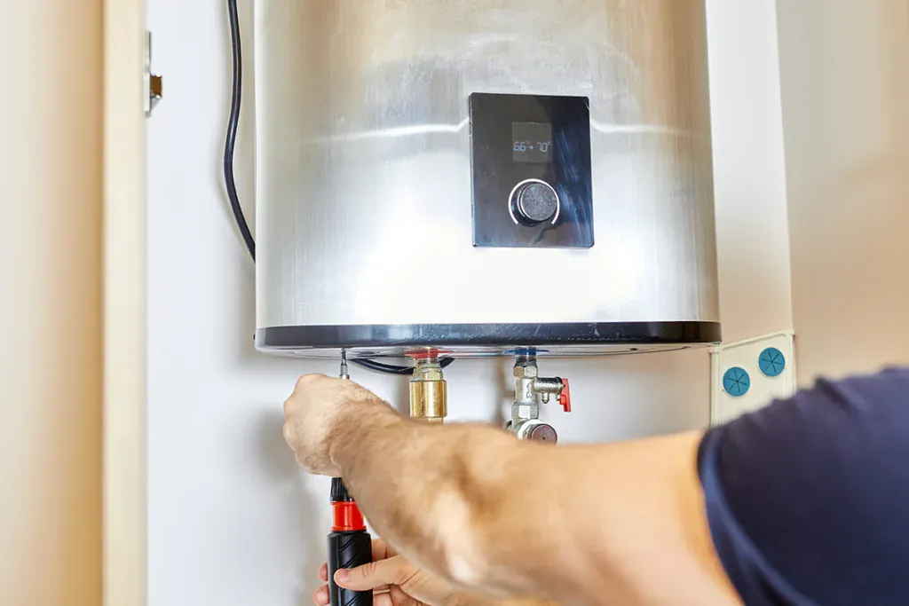 Technician using a screwdriver on the valves under a wall-mounted water heater