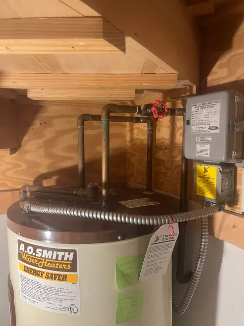Before: Top of an older A. O. Smith water heater with copper supply pipes, a red shutoff valve and handwritten notes