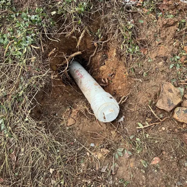 Before: Broken sewer cleanout pipe sticking out of a hole in the yard.