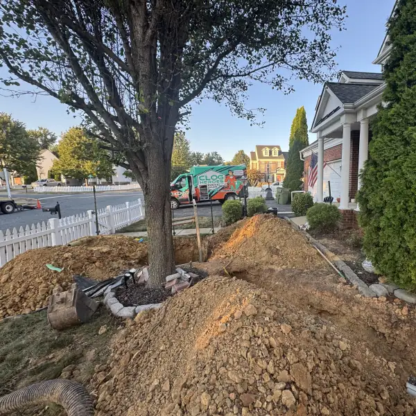 Front-yard sewer trench with the service van parked at the curb.