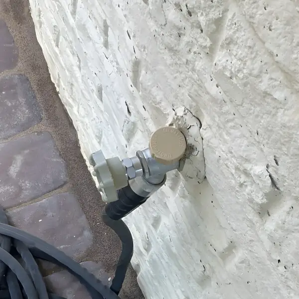 After: New hose bib installed on the painted brick wall.