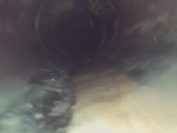 Before: Sewer camera view of grease and debris lining the sewer pipe.