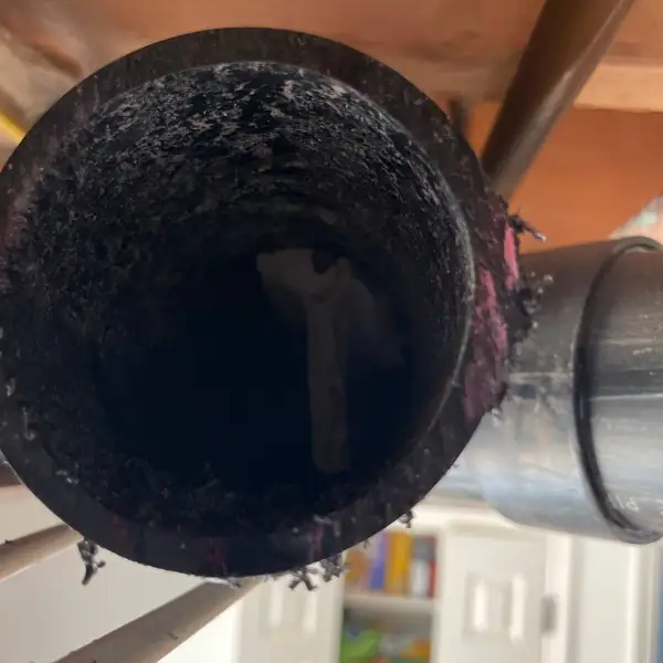 Cut cast iron drain pipe showing heavy scale inside.