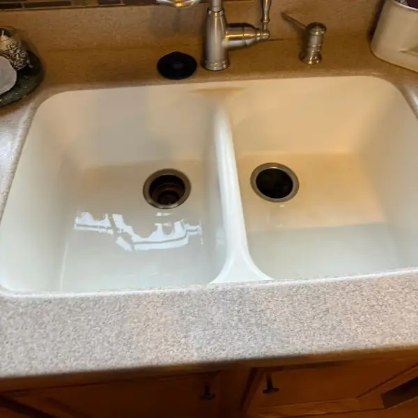 After: The same kitchen double sink empty and draining after the clog was cleared.