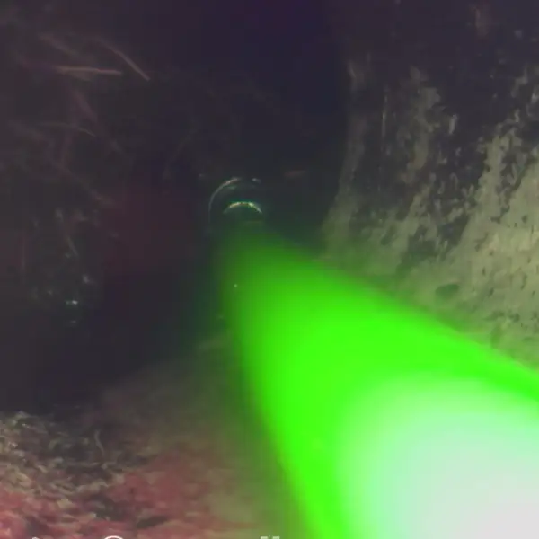 Sewer camera view of the jetter nozzle firing into a dirty sewer line.