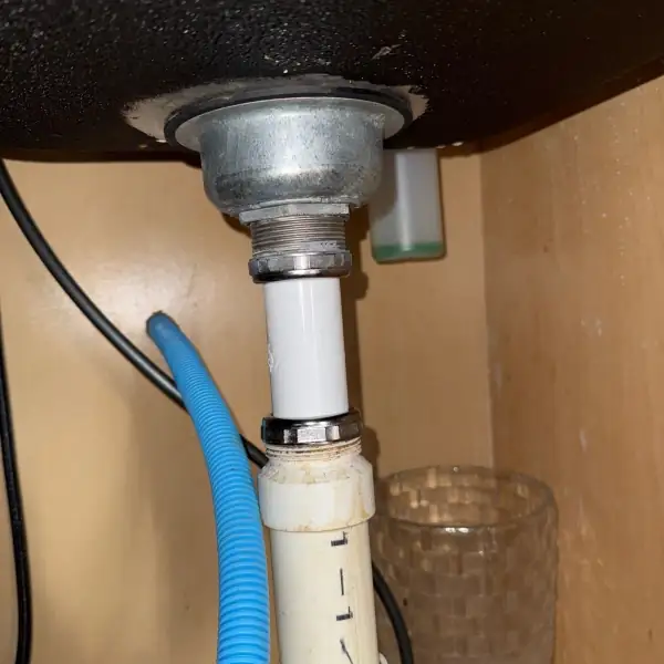 After: New PVC drain tailpiece installed under the vanity sink.