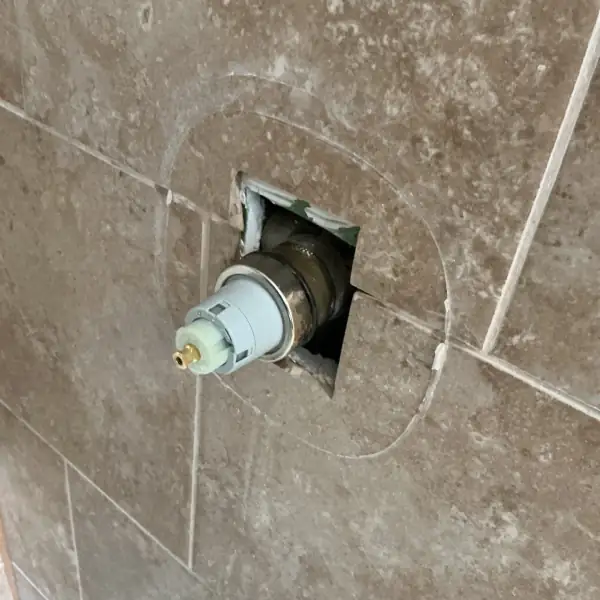 Shower valve cartridge exposed in the tile during the repair.