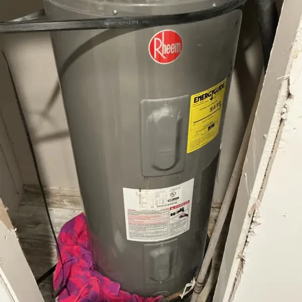 Before: Old tank water heater in a utility closet.